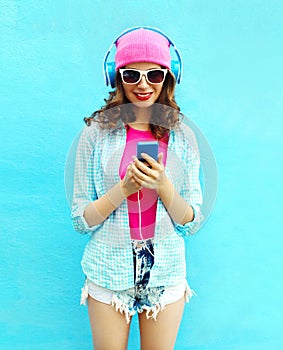 Pretty cool woman listens to music in headphones using smartphone