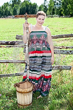 Pretty country woman with wooden rake and bucket