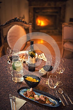 Pretty couple drinking red wine and eating in restaurant, winter time, romantic dinner