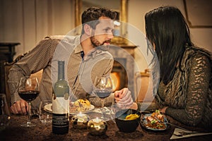 Pretty couple drinking red wine and eating in restaurant, winter time, romantic dinner