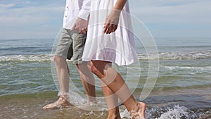 Pretty couple of young lovers walk along the beach