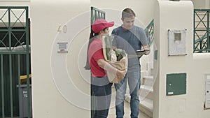 Pretty courier girl in red uniform delivering food