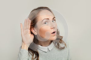 Pretty curious nosy woman listening on white background