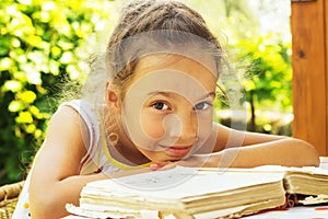 Pretty curly school girl reading an old book outside