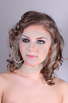 Pretty curly woman with makeup poses with earrings