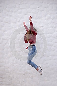 Pretty curvy girl jumping sideways next to a peculiar white wall