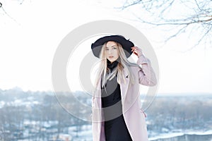 Pretty cute beautiful young woman with blond hair in a vintage pink coat in a stylish hat in golf in a skirt is stands on the