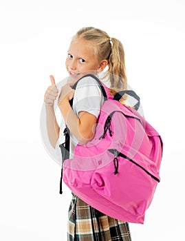 Pretty cute blonde hair girl with a pink schoolbag looking at camera showing thumb up gesture happy to go to school isolated on