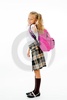 Pretty cute blonde hair girl with a pink schoolbag looking at camera showing thumb up gesture happy to go to school isolated on