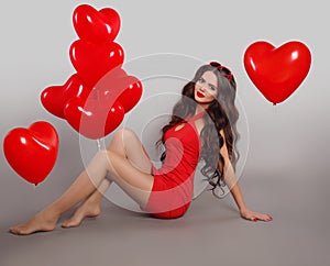 Pretty cute brunette girl in red dress with heart shape balloons photo