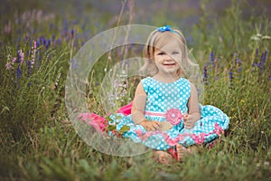 Pretty cute little girl is wearing white dress in a lavender field holding a basket full of purple flowers