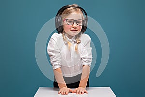 Pretty, cute little girl in white shirt, glasses, black trousers and headphones