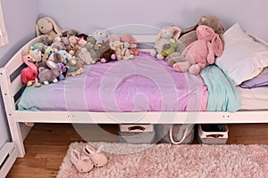 Pretty decorated girls bedroom with simple bed and plush stuffies