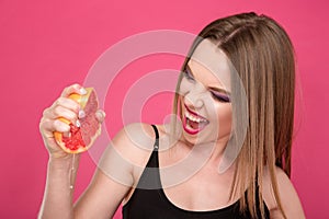 Pretty delighted woman squeezing grapefruit juice by hands