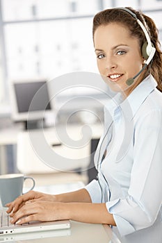 Pretty dispatcher working in bright office smiling