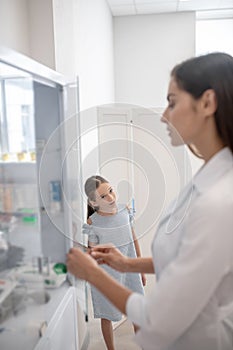 Pretty doctor in a lab coat opening a vitrine with medicines