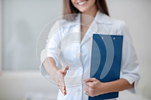 Pretty doctor in a lab coat smiling and welcoming the patient