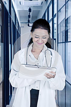 Pretty doctor using digital tablet in corridor