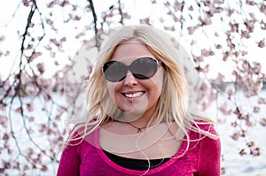 Pretty dusk sunset portrait of a Blonde Woman posing by Cherry Blossom flowers