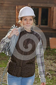 Pretty electrician in helmet holding electric cable