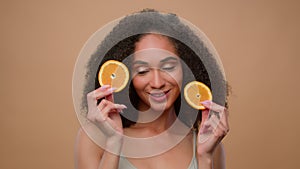 Pretty ethnic model African American girl holding two slices of citrus woman hold half of orange cosmetology skin care