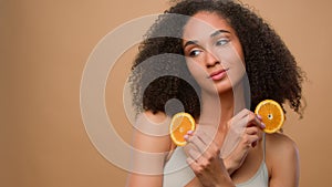 Pretty ethnic model African American girl holding two slices of citrus woman hold half of orange cosmetology skin care