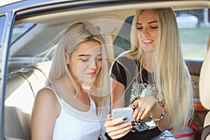 The pretty european girls 25-30 years old in the car make photo on mobile phone