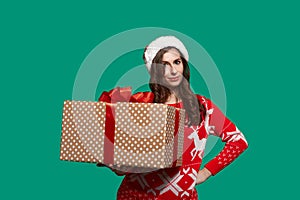 Pretty european woman with dark hair holds a big gift box with bow knot, getting ready to give presents, wears red ugly