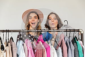 Pretty excited young women shopaholics choosing clothes.