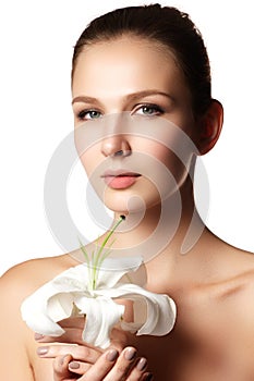 Pretty face of beautiful young woman with lily on hands - white