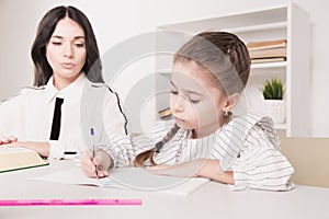 Pretty family concept. Mom and daughter sitting together and studying at home.