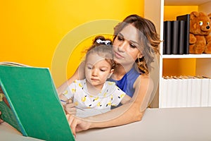 Pretty family concept. Mom and daughter sitting together and studying at home.