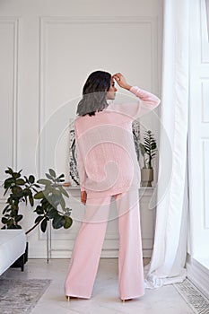 Pretty fashion beautiful woman sexy lady brunette curly hair dark tanned skin wear trend clothes knitted pink pink suit jacket top