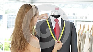 Pretty fashion designer measuring suit lapels on mannequin