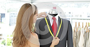 Pretty fashion designer measuring suit lapels on mannequin