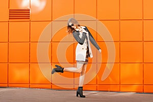 Pretty fashion woman in dress and sunglasses.Background of a bright orange wall.