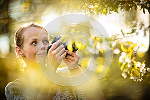 Pretty female amateur photographer taking photos outdoors