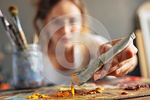 Pretty female artist painting with a brush on canvas in her art studio. Out of focus woman painter painting with oil searching for