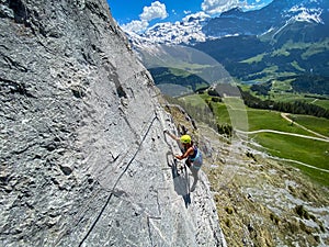 Pretty female climber on a steep Via Ferrata in the Swiss Alps