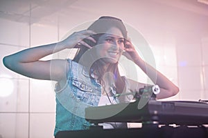 Pretty female DJ listening to the headphone while playing music