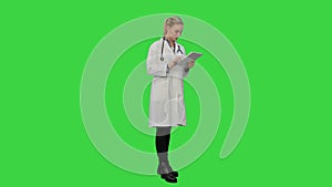 Pretty female doctor with stethoscope glad to get a good results using digital tablet on a Green Screen, Chroma Key.