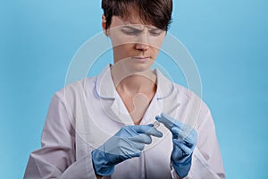 Pretty female doctor wearing white medical robe holding syringe at blue background. treatment and prevention coronavirus