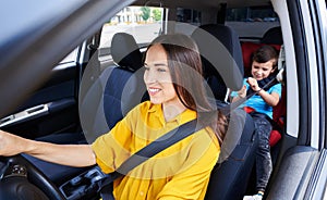 Pretty female driving car with son sitting in baby seat