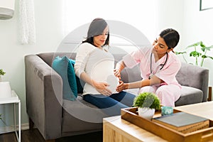 Pretty female nurse checking the belly of an expectant mother