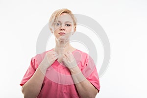 Pretty female nurse wearing pink scrubs arranging shirt