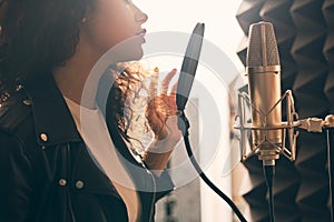 Pretty female singer recording in music studio