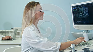 Pretty female sonographer working at ultrasound equipment photo