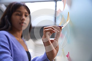 Pretty female sticking sticky notes in modern room