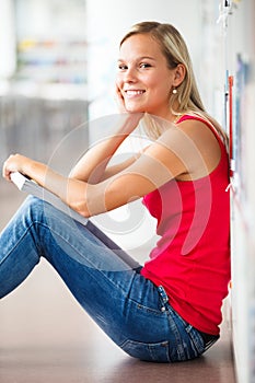 Pretty female student with books working in a high school library