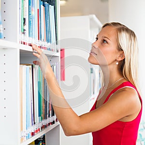 Pretty female student with books working in a high school library